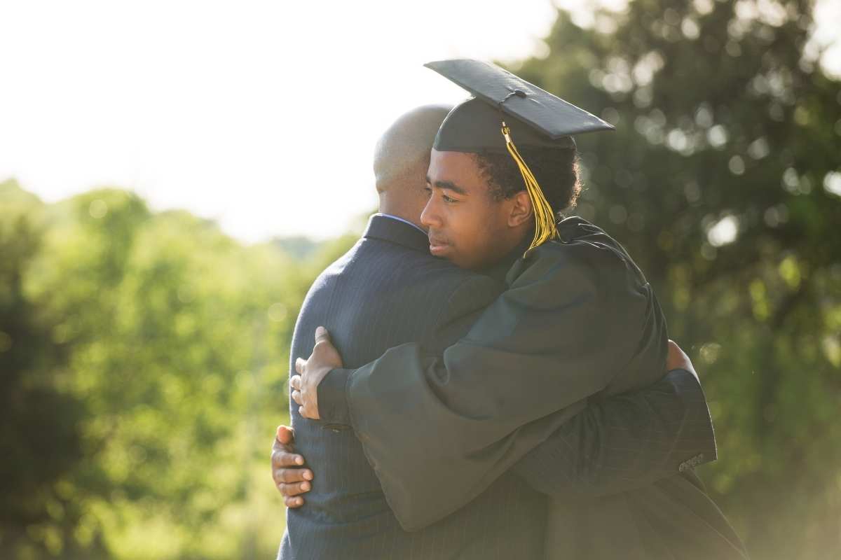 graduate in cap and gown hugging person