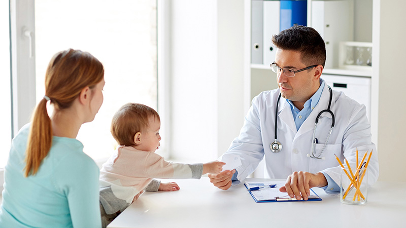 Male doctor talking to mother and baby