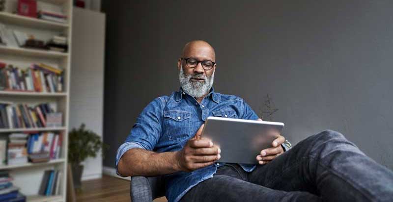 man reclining in chair reading tablet