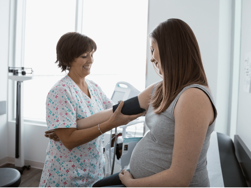 Nurse taking pregnant woman's blood pressure.