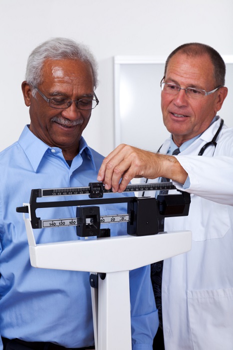 Man being weighed by doctor 467x700