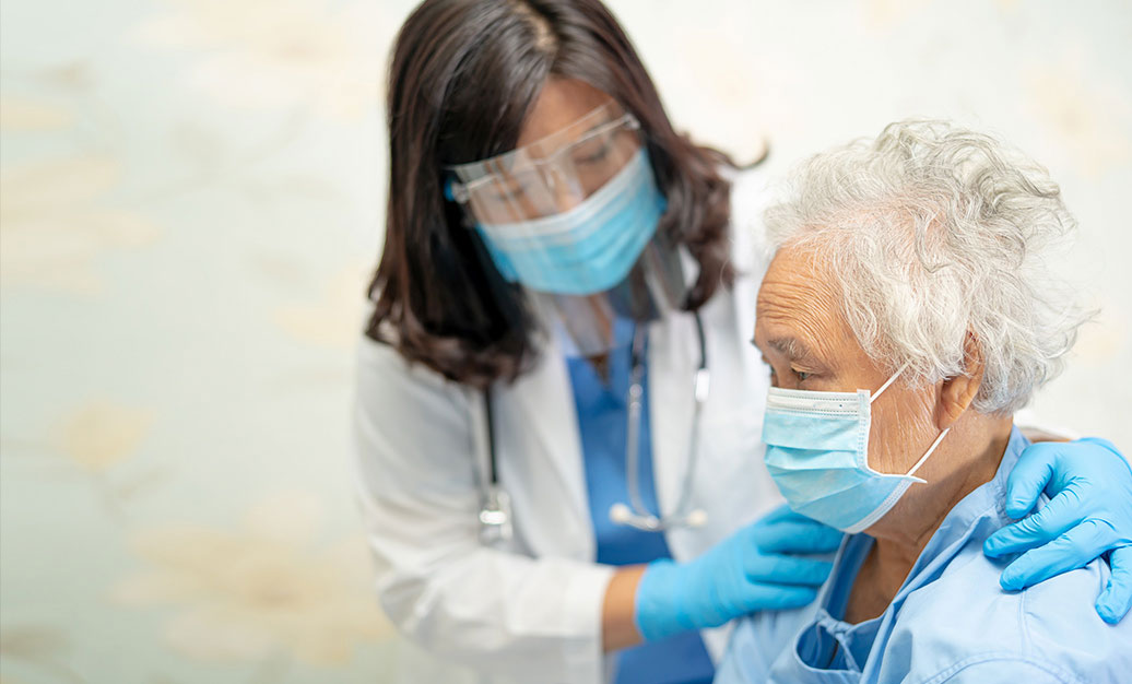 female doctor with elderly female patient. both wearing protective masks