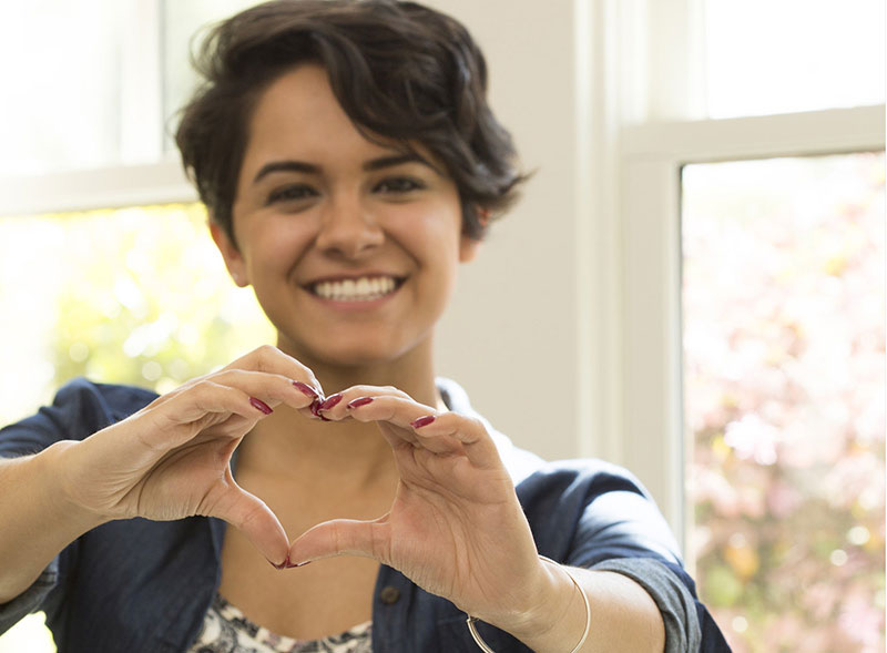smiling Woman making heart hand gesture smiling Woman making heart hand gesture