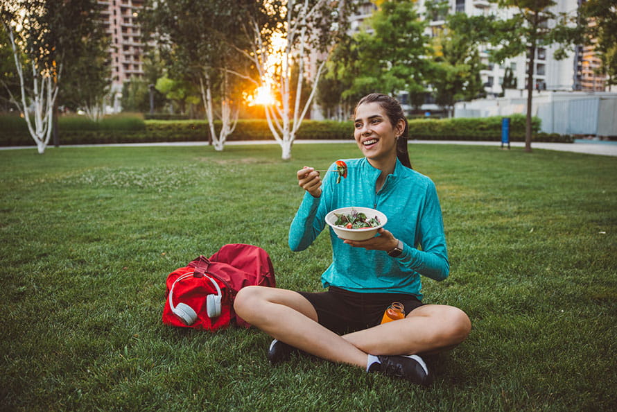 Woman eating a salad in the park after a workout